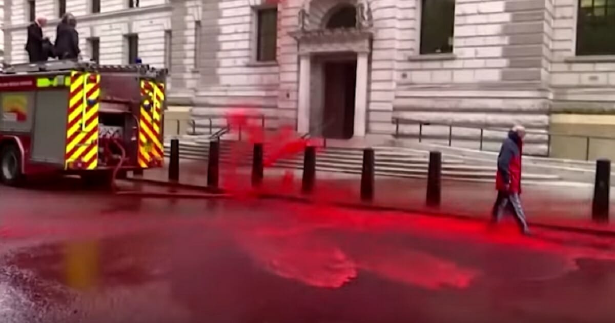 Fake "blood" sprays from a burst hose at a climate change protest in London on Thursday.
