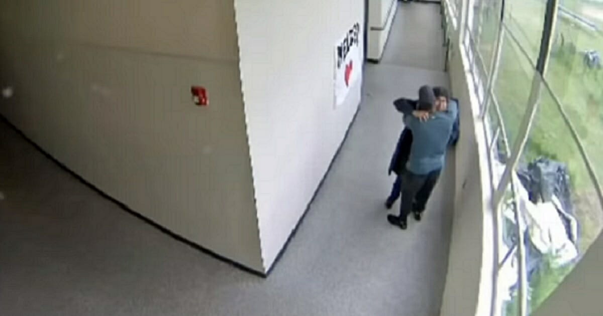 Keanon Lowe, a football coach, track coach and security guard at Parkrose High School in Portland, Oregon, embraces a student who came to school in May armed with a shotgun and planning to end his life.