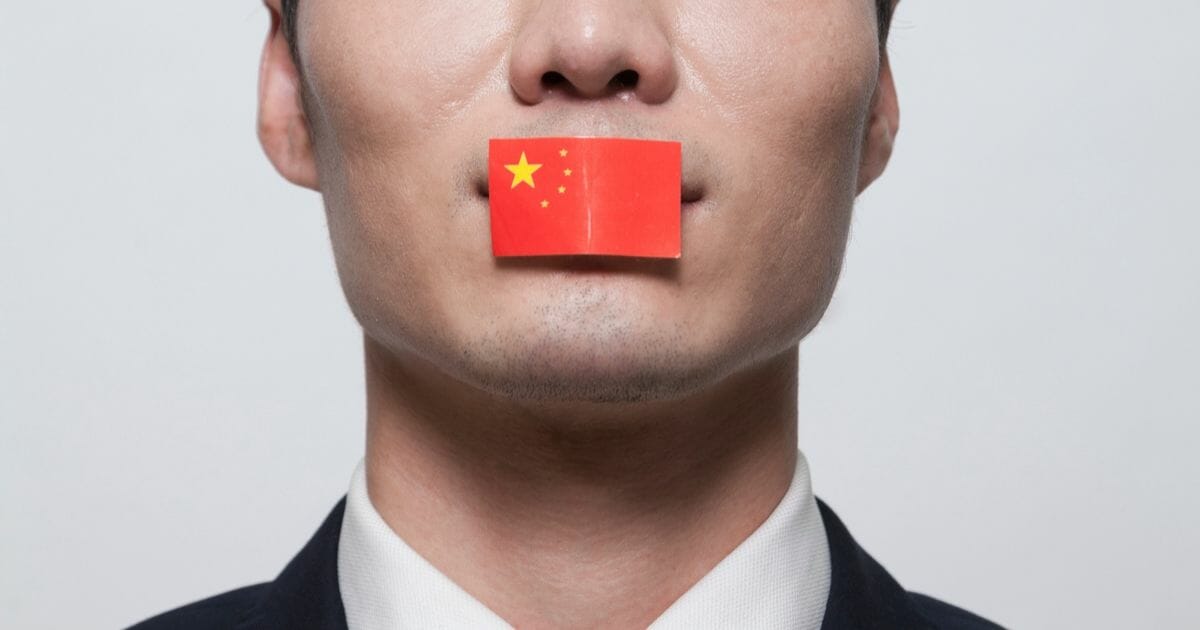 Stock photo of a Chinese flag covering up a man's mouth.