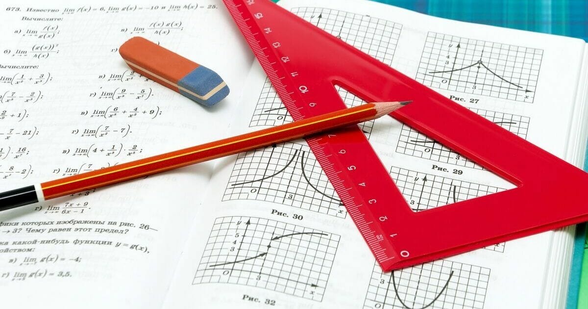 Stock image of school supplies resting on an open math textbook.