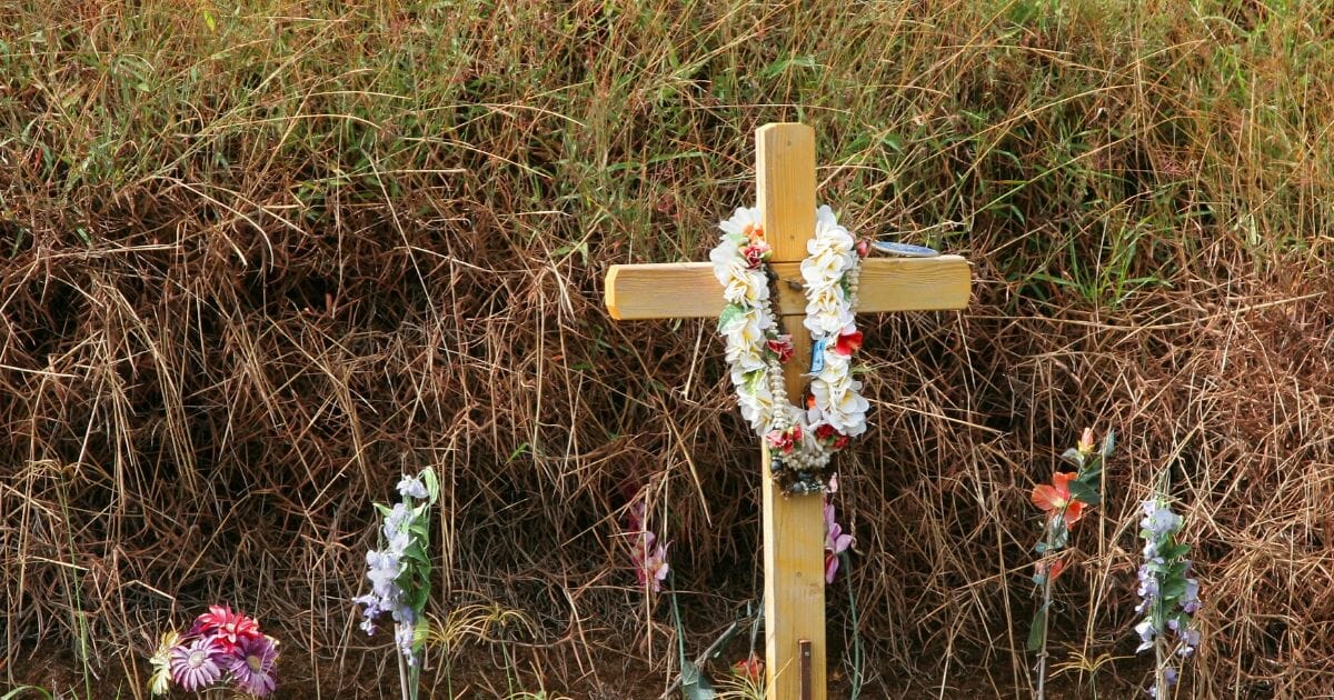 Stock image of a roadside cross on a highway set up as a memorial.