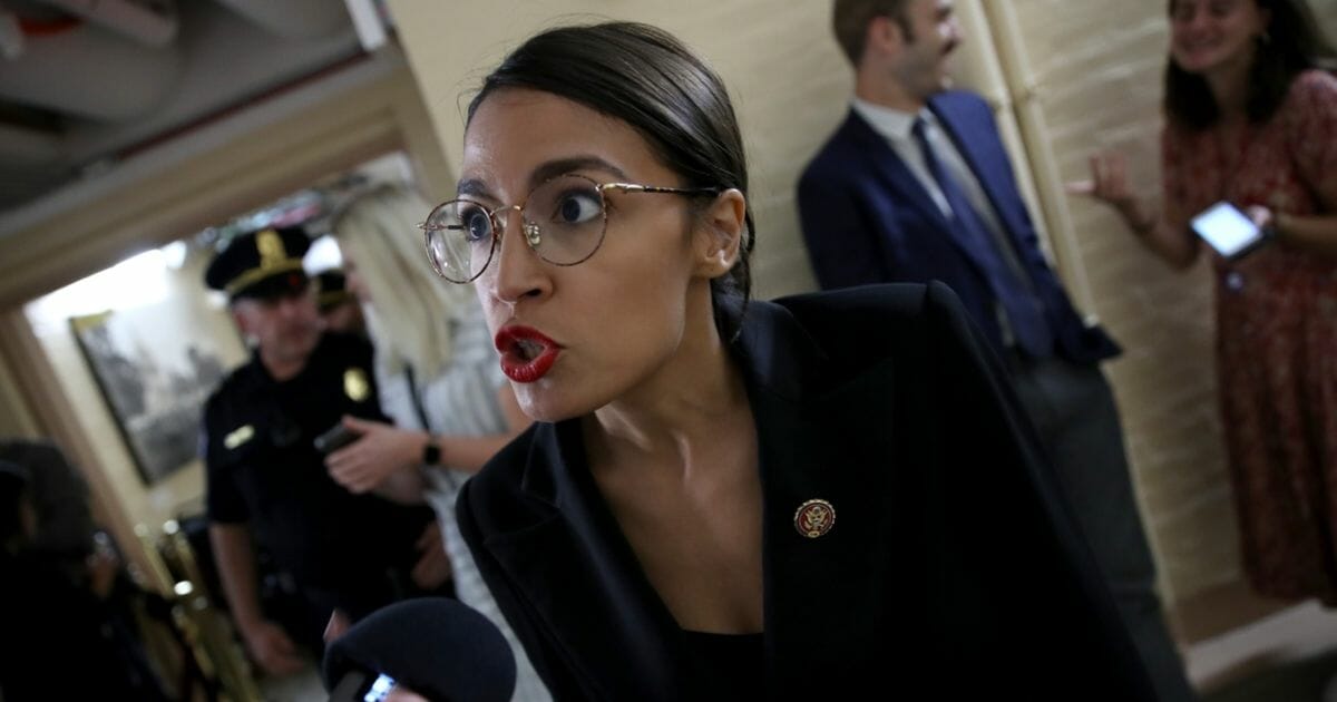 Rep. Alexandria Ocasio-Cortez answers questions from reporters while entering a House Democratic caucus meeting at the U.S. Capitol.