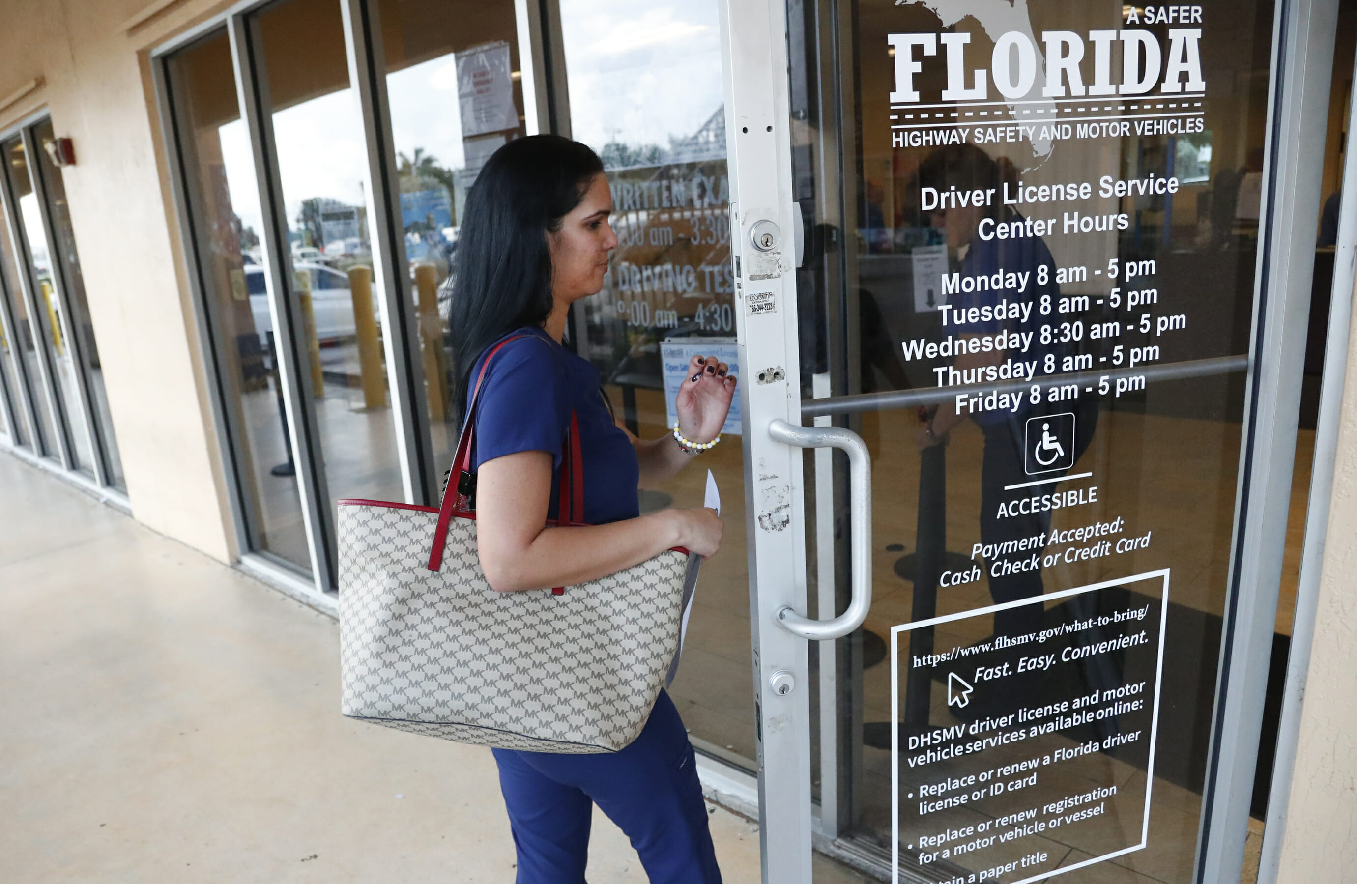 A woman enters a Florida Highway Safety and Motor Vehicles drivers license service center, Tuesday, Oct. 8, 2019, in Hialeah, Fla.