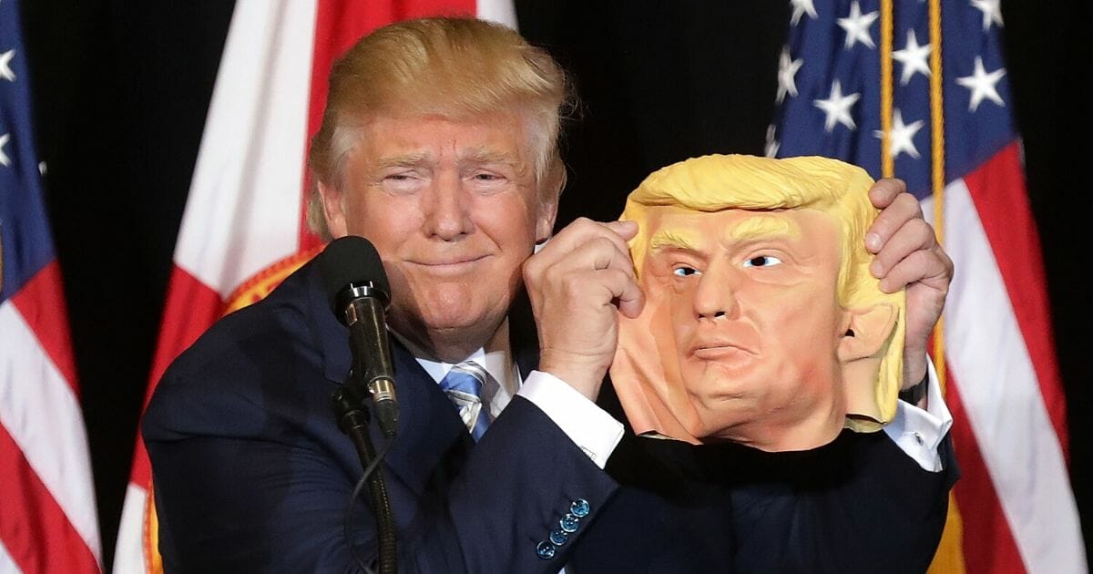 Republican presidential nominee Donald Trump holds up a rubber mask of himself during a campaign rally.