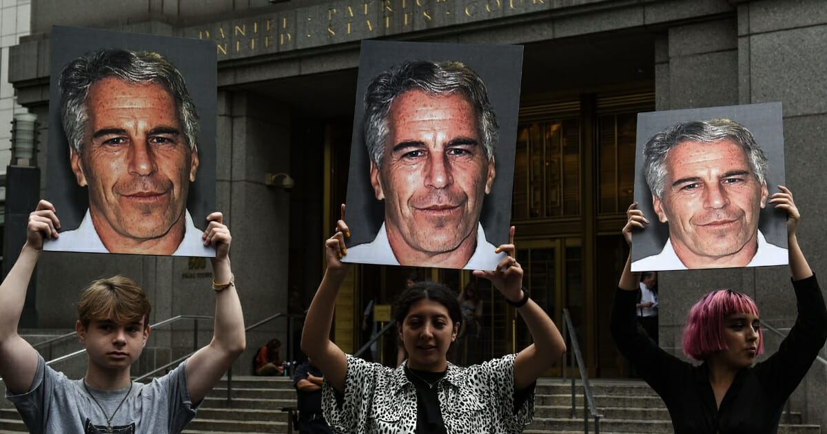 A protest group called "Hot Mess" holds up signs of Jeffrey Epstein in front of the federal courthouse on July 8, 2019, in New York City.