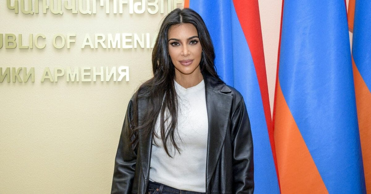 U.S. reality television star Kim Kardashian poses by Armenian flags at the Armenian Government building during her visit in Yerevan on Oct. 9, 2019.