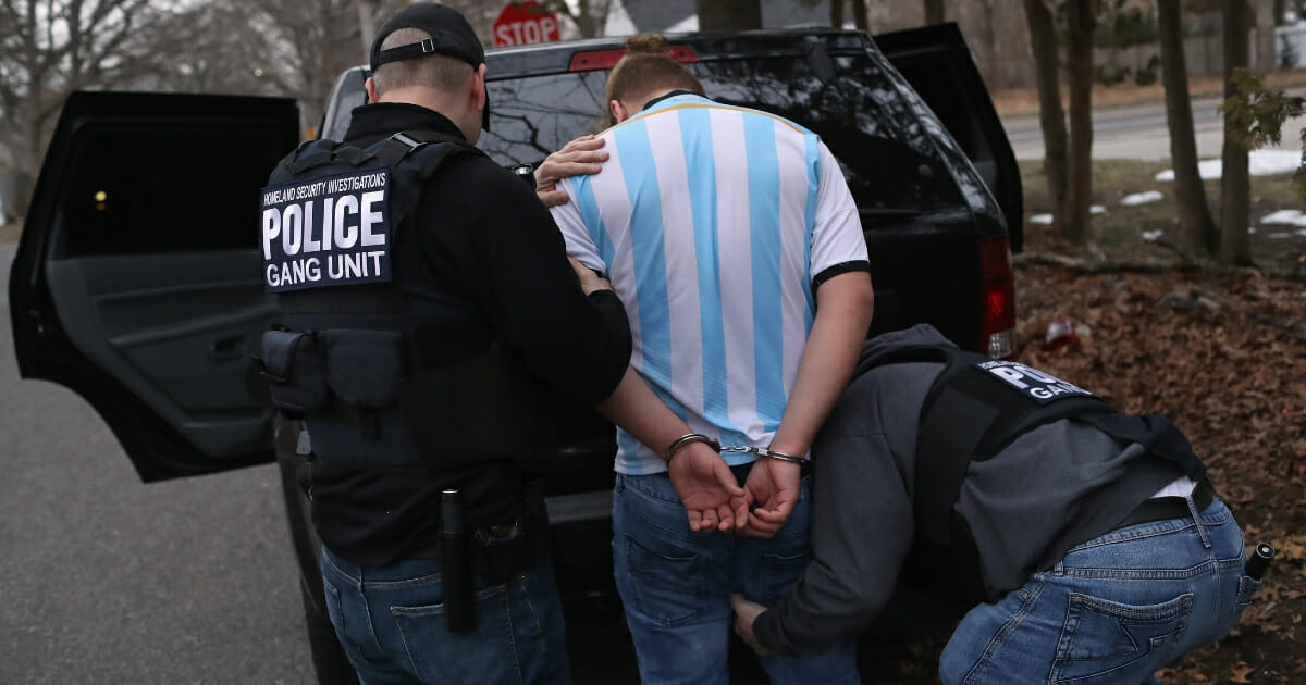 ICE agents frisk a suspected MS-13 gang member after arresting him at his home in Brentwood, New York.