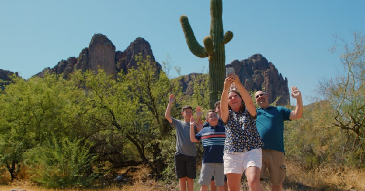 A family takes a photo in front of a cactus in Mesa, Arizona.