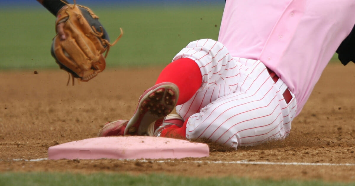 A baseball player slides into third base before the tag.