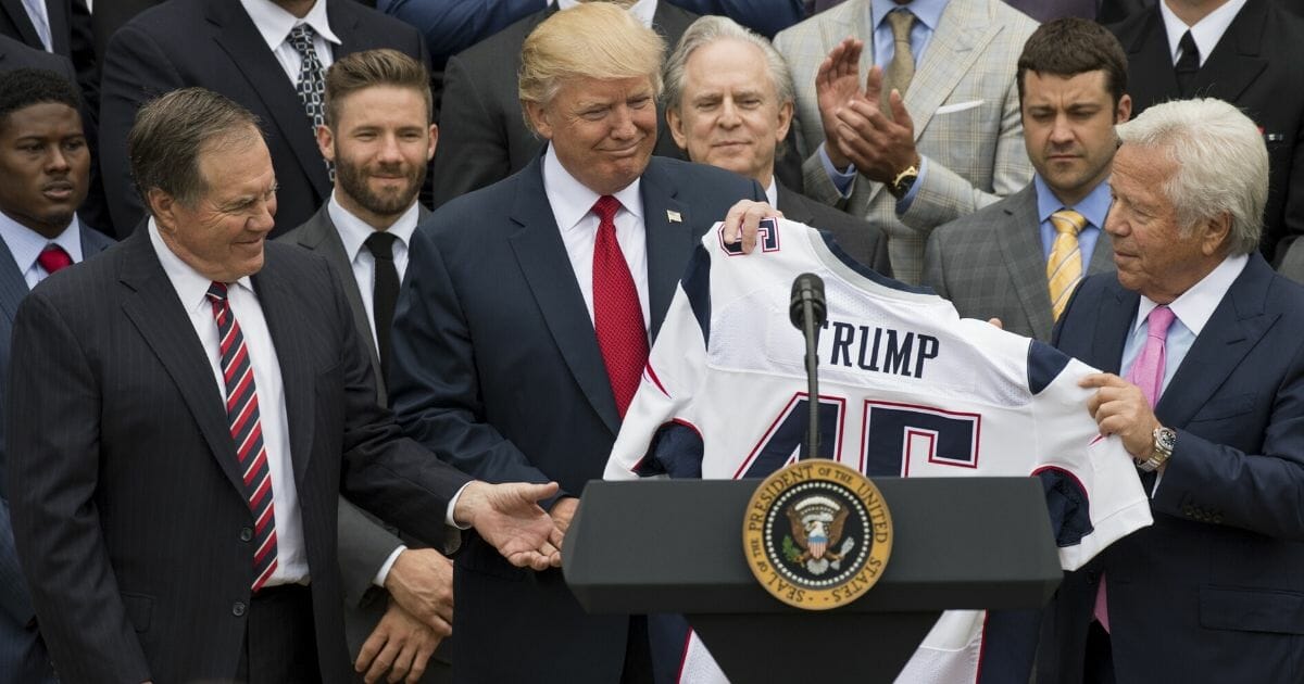 President Donald Trump holds a jersey given to him by New England Patriots owner Robert Kraft, right, and head coach Bill Belichick, left, alongside members of the team during a ceremony honoring them as 2017 Super Bowl champions on the South Lawn of the White House in Washington, D.C., on April 19, 2017.