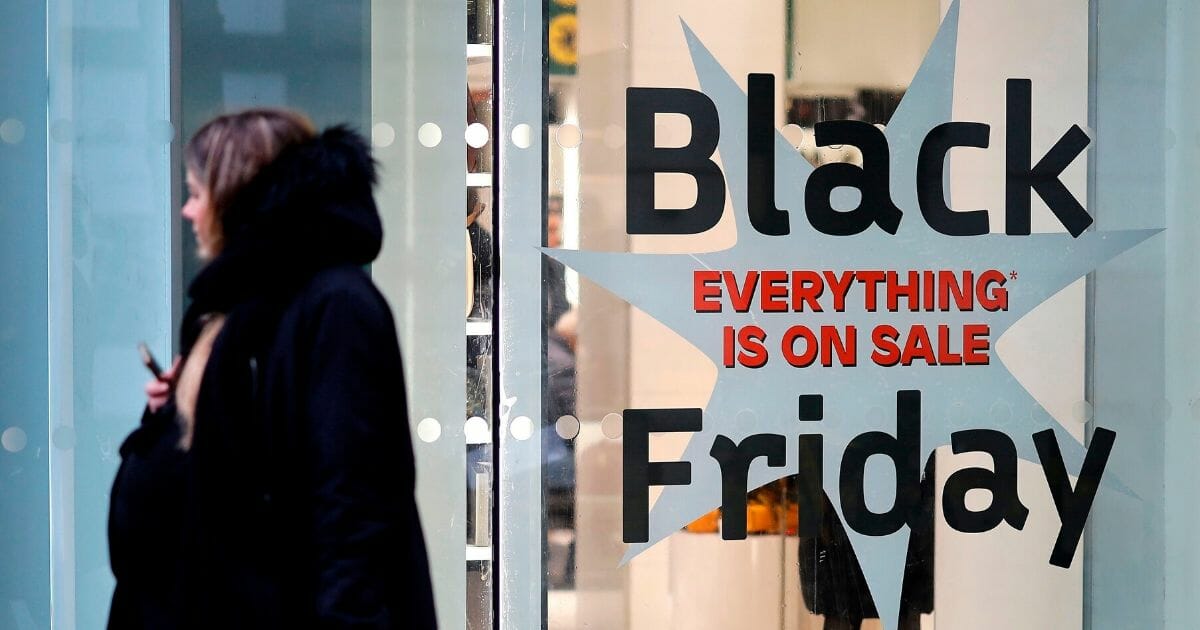 Shoppers pass promotional Black Friday sign in London