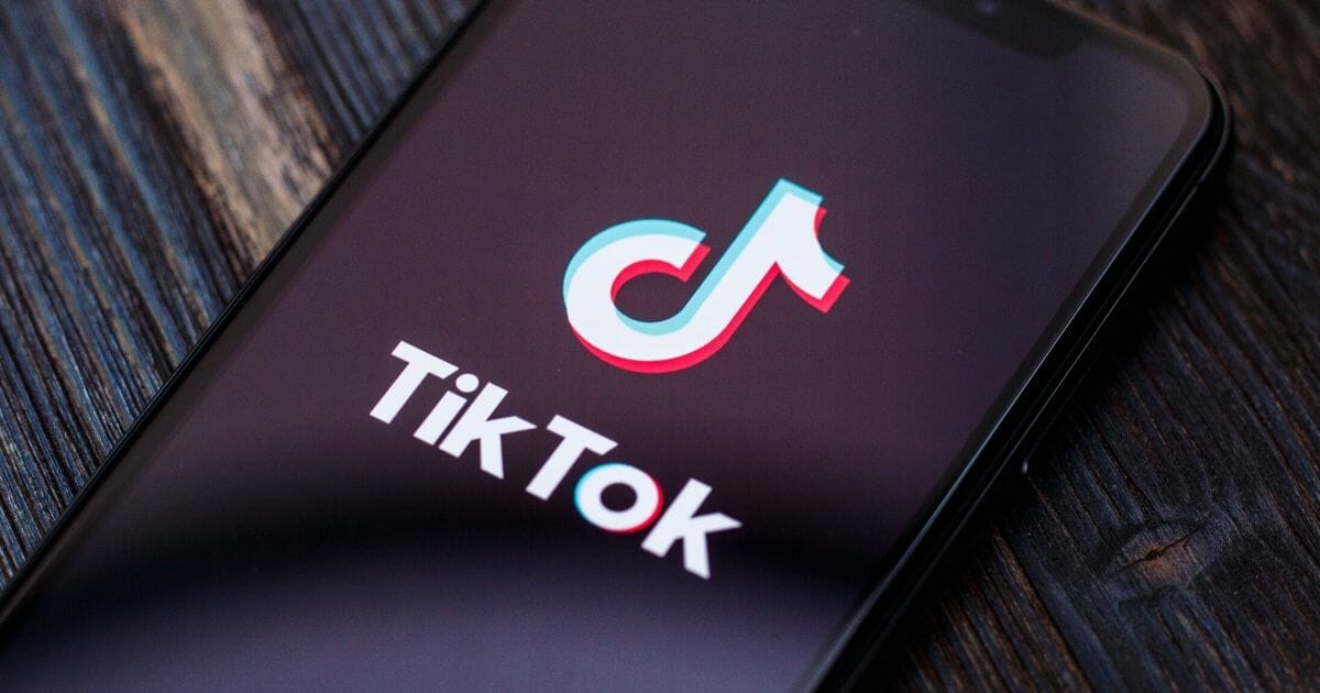 Tik Tok application icon on Apple iPhone X screen close-up.