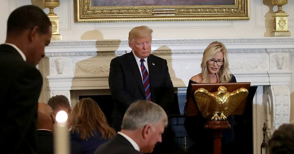 President Donald Trump bows his head as Pastor Paula White, right, delivers a prayer before dinner for guests celebrating evangelical leadership at the White House on Aug. 27, 2018, in Washington, D.C.