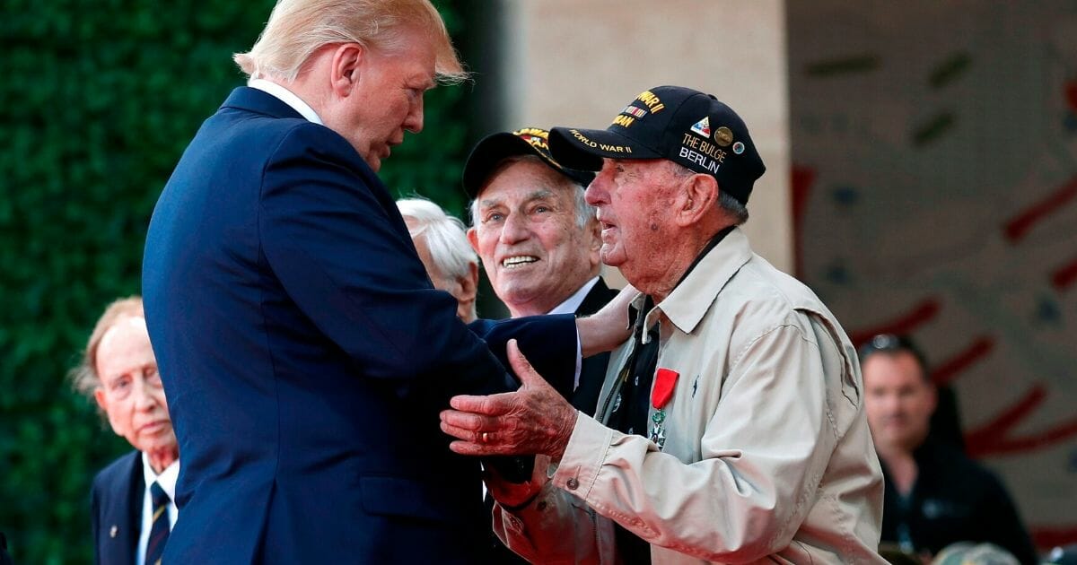 President Donald Trump greet a U.S. veteran during a French-U.S. ceremony at the Normandy American Cemetery and Memorial.