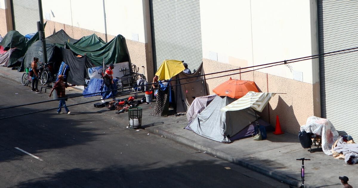 People walk past a homeless tent encampment in Skid Row on September 16, 2019 in Los Angeles, California.