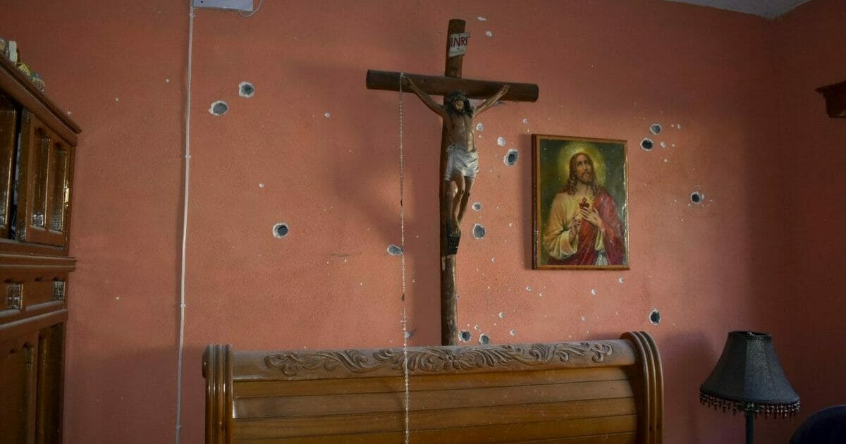 A wall of the room of a home is riddled with bullet holes