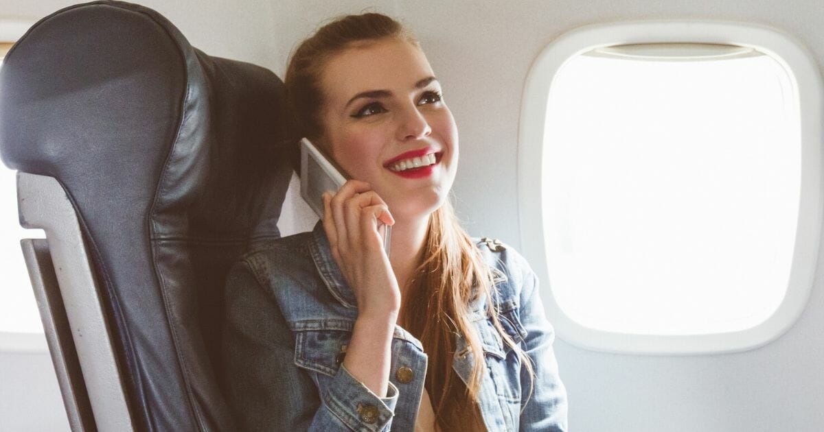 A passenger uses her cellphone during a flight.