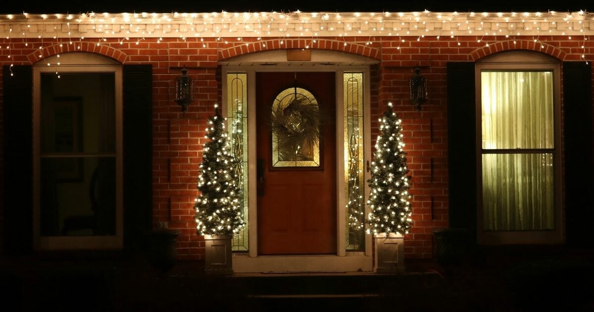 The doorway of a house adorned with Christmas lights and other decorations.