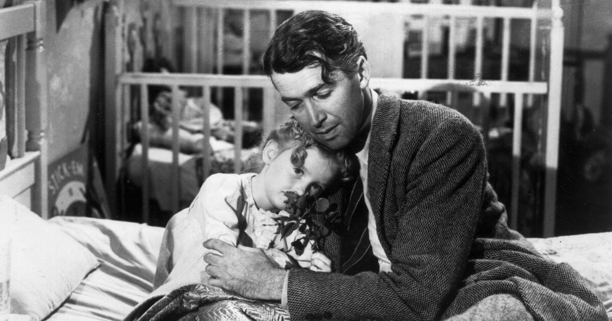 American actor James Stewart (1908 - 1997) as George Bailey, hugs actor Karolyn Grimes, who plays Zuzu his daughter, in a still from director Frank Capra's Christmas classic film, 'It's a Wonderful Life.'