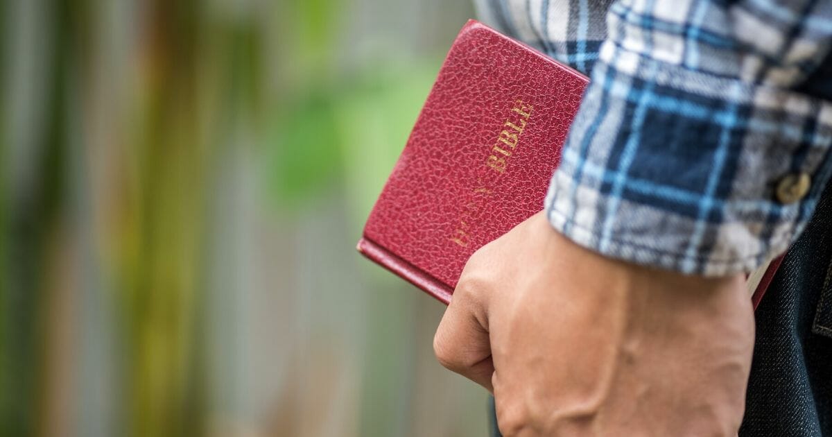 The stock image above shows a person holding a Christian Bible.