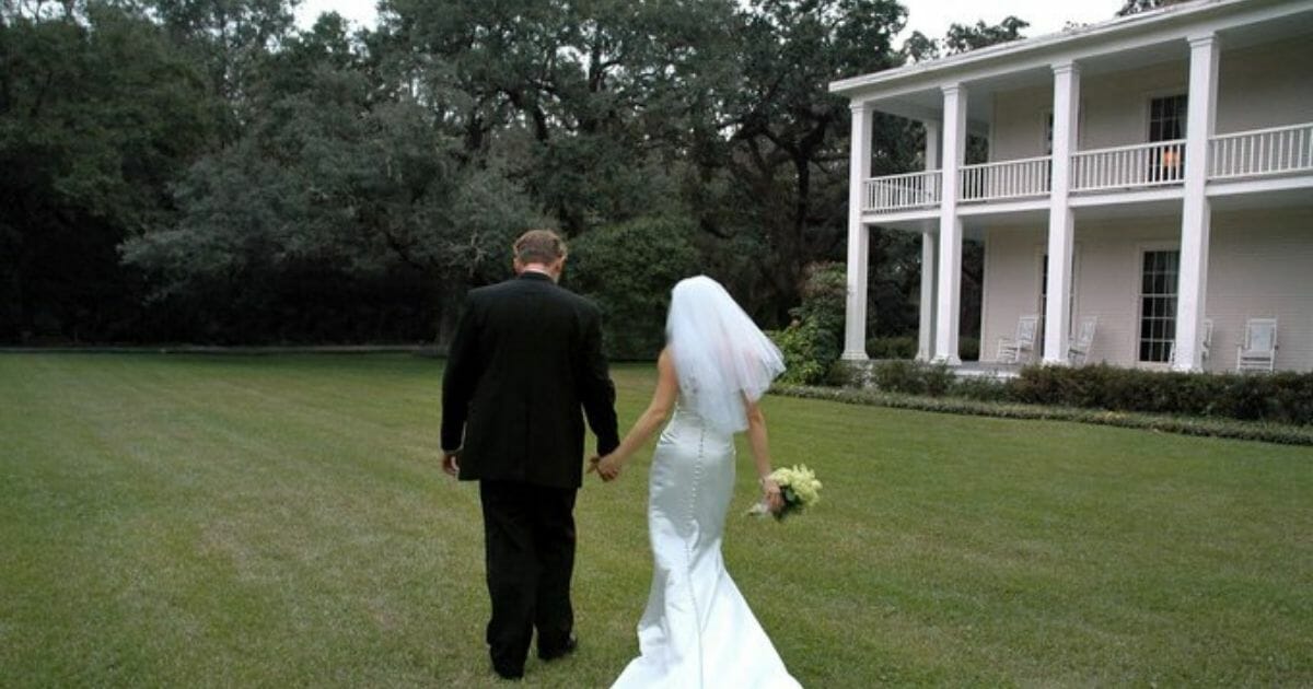 A bride walks across the lawn of a plantation site.