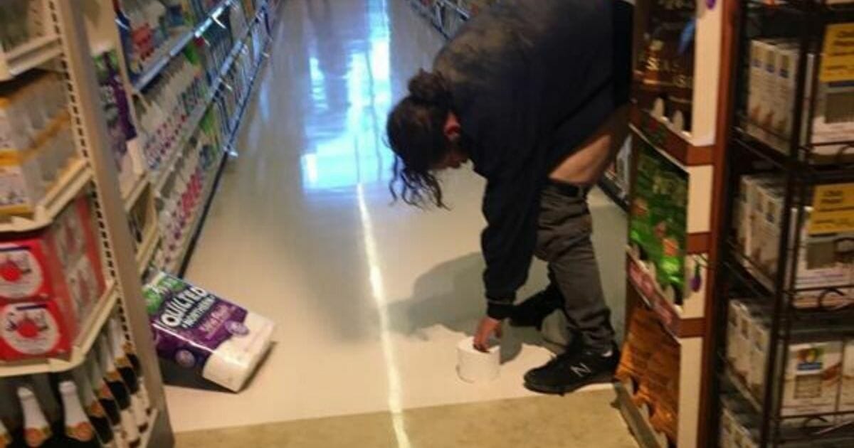 A man in the act of using a Safeway aisle as his own personal toilet.
