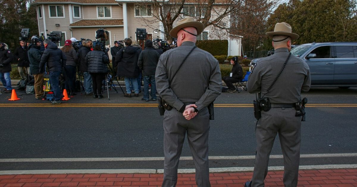 Law enforcement stands guard Sunday as reporters gather outside a rabbi's home where a machete attack took place Saturday during the Jewish festival of Hanukkah, in Monsey, New York.