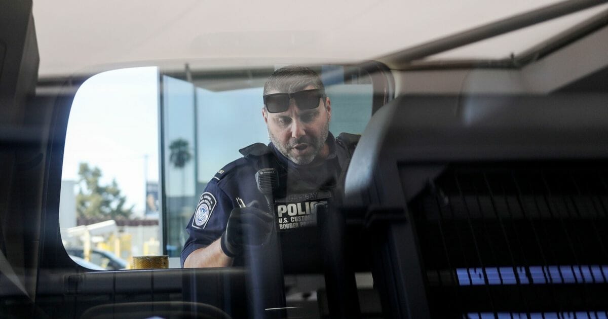An Immigration and Customs Enforcement agent checks an automobile for contraband in the line to enter the United States at the San Ysidro Port of Entry on Oct. 2, 2019, in San Ysidro, California.