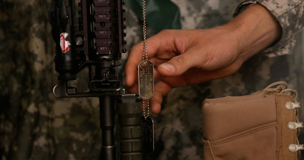 A U.S. soldier touches the dog tags of a slain comrade during a memorial service June 8, 2010, in Belanday, south of Kandahar, Afghanistan.