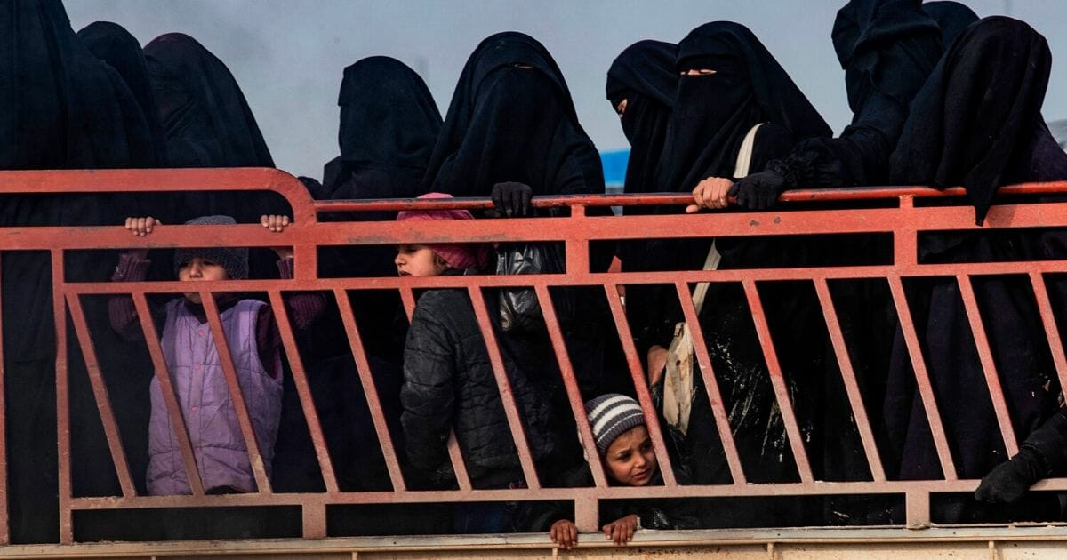 Women and children ride in the back of a truck