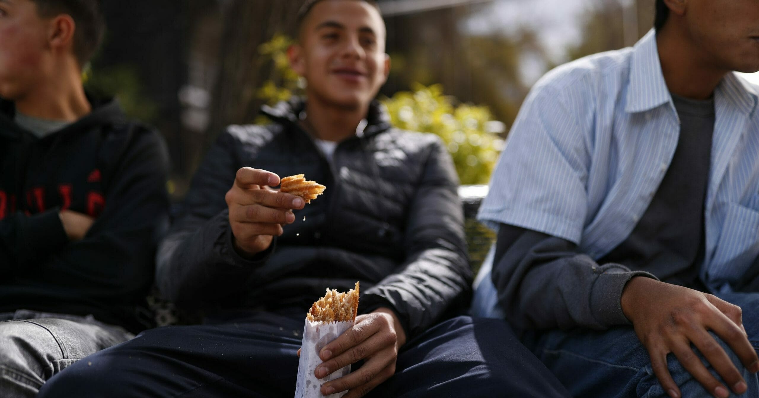 A young man eats churros packaged in a thin paper bag, purchased from a walking vendor carrying his wares in a woven basket, in Mexico City on Dec. 31, 2019. A new law takes effect Jan. 1, 2020, prohibiting the plastic bags that became ubiquitous over the last 30 years.