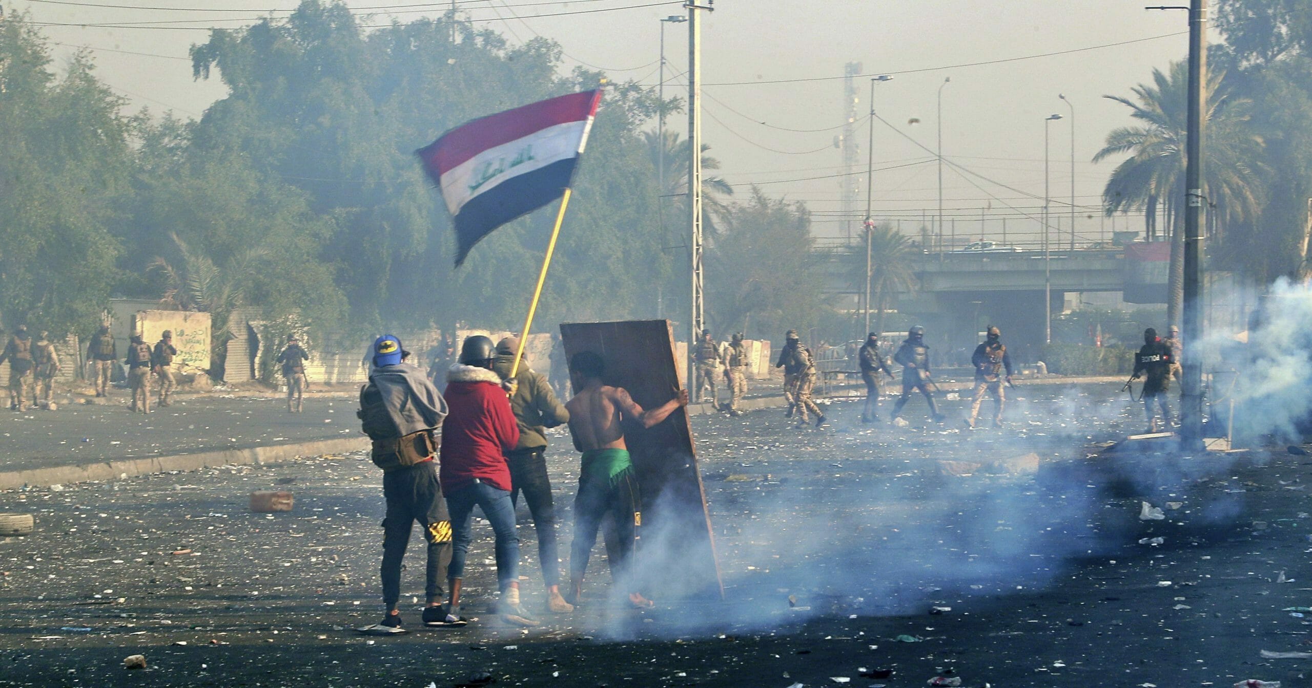 Protesters wave the Iraqi national flag as security forces fire tear gas during an ongoing protest in central Baghdad on Jan. 20, 2020.