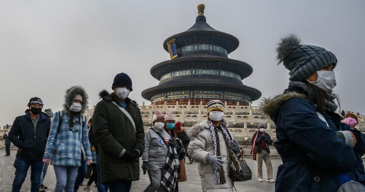 Visitors wear masks to protect themselves from coronavirus as they tour the grounds of the Temple of Heaven in Beijing on Jan. 27, 2020.