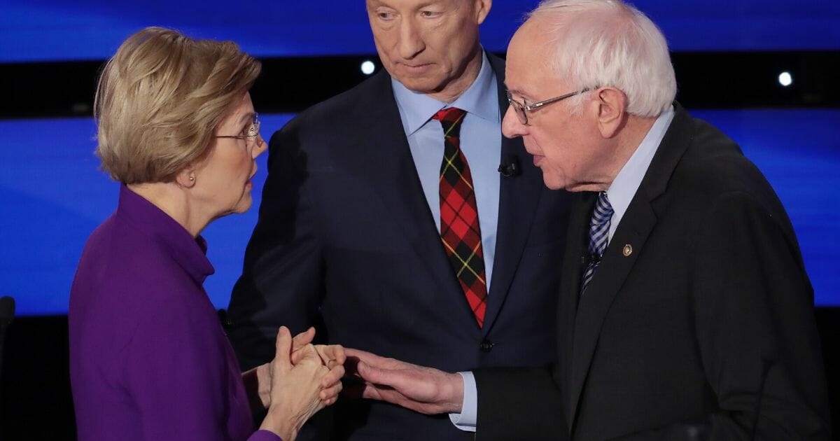 Sen. Elizabeth Warren (D-Massachusetts) and Sen. Bernie Sanders (I-Vermont) speak as Tom Steyer looks on after the Democratic presidential primary debate at Drake University on Jan. 14, 2020, in Des Moines, Iowa.