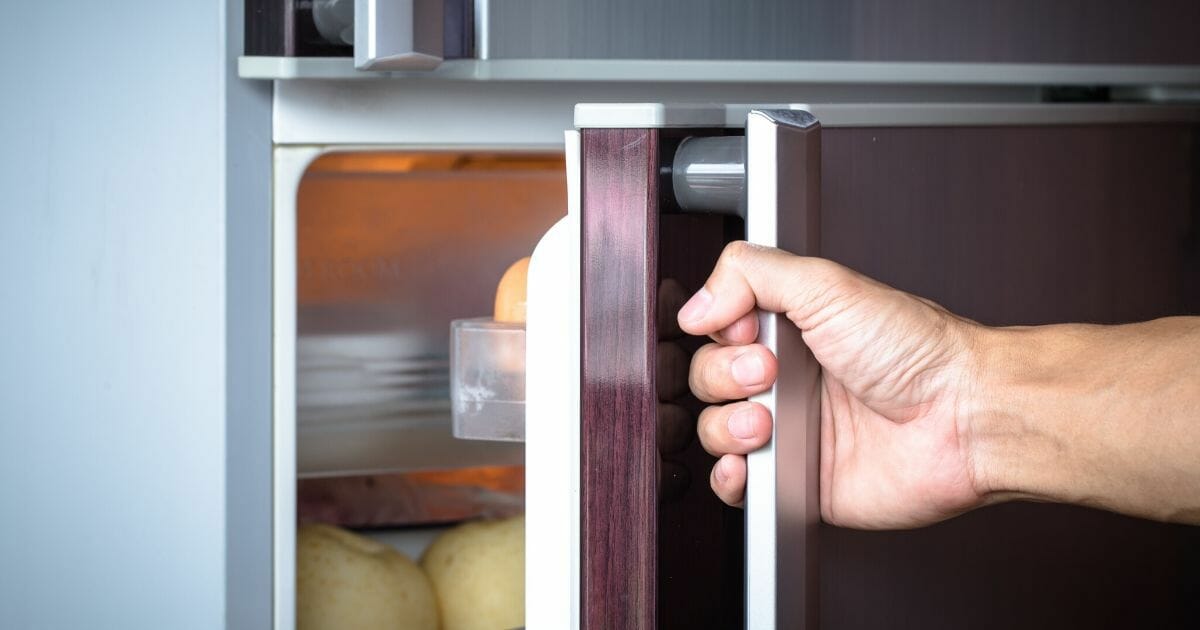 Stock image of a man opening a refrigerator door.