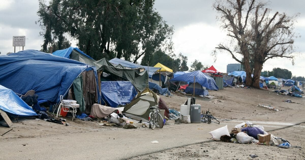 A stock photo of a homeless encampment is seen above.