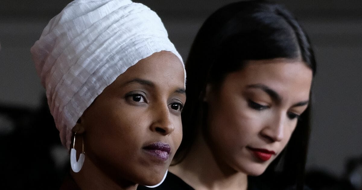 Reps. Ilhan Omar (D-Minnesota), left, and Alexandria Ocasio-Cortez (D-New York) listen during a news conference at the U.S. Capitol on July 15, 2019, in Washington, D.C.