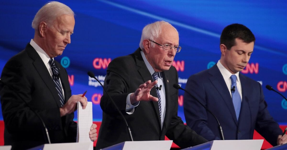 Former South Bend, Indiana, Mayor Pete Buttigieg, right, and former Vice President Joe Biden, left, listen as Sen. Bernie Sanders (I-Vermont) makes a point during the Democratic presidential primary debate at Drake University on Jan. 14, 2020, in Des Moines, Iowa.