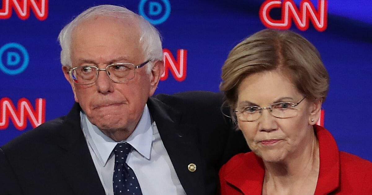 Democratic presidential candidates Sen. Bernie Sanders and Sen. Elizabeth Warren stand together after a primary debate at the Fox Theatre in Detroit on July 30, 2019.
