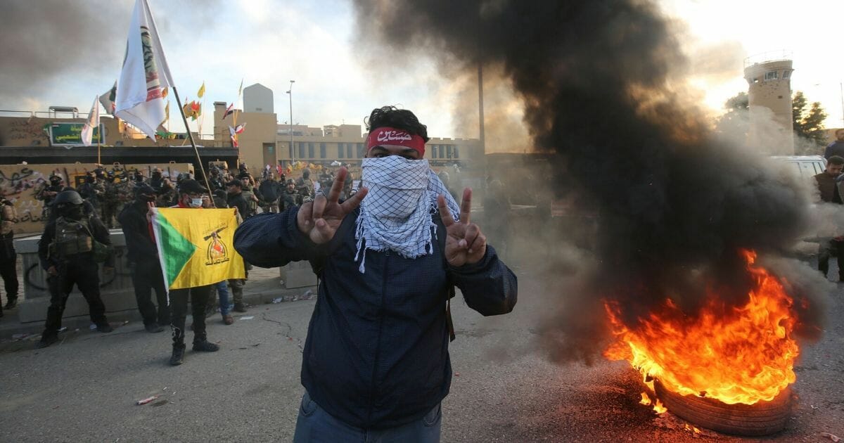 A supporter of Iraq's Hashed al-Shaabi paramilitary force flashes victory signs during a protest outside the U.S. Embassy in the Iraqi capital city of Baghdad on Jan. 1, 2020, to condemn the US air strikes that killed 25 Hashed fighters over the weekend.