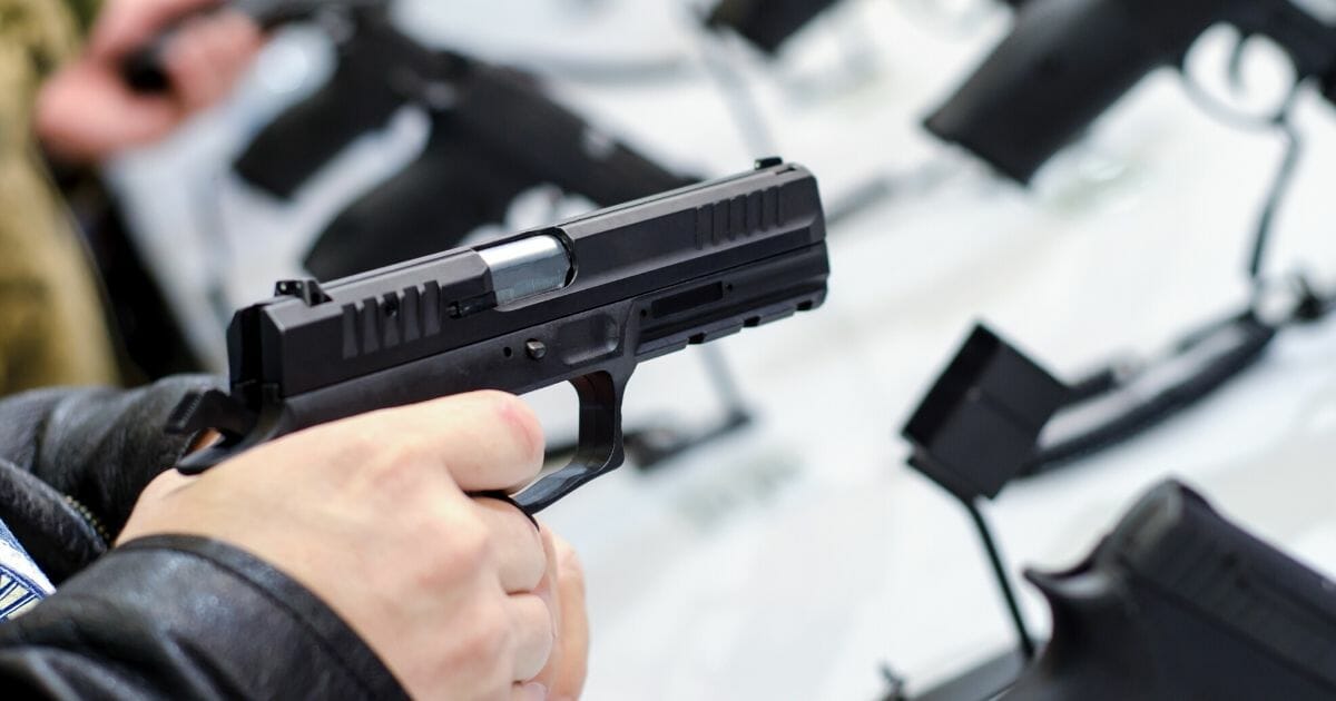 Man pointing a handgun at a gun store.