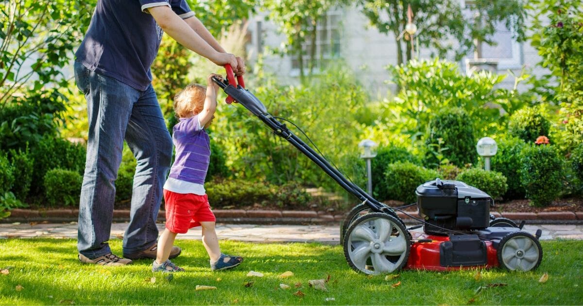 Stock photo of a man and his son mowing the lawn.