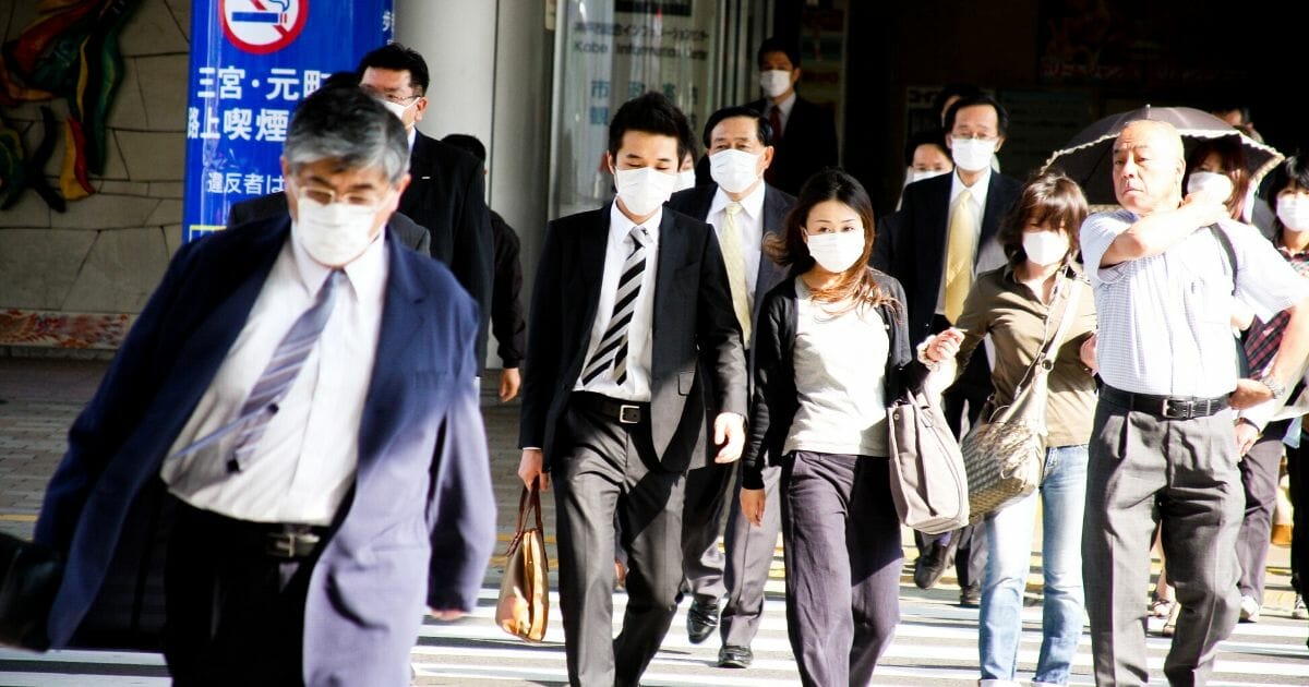 Stock image of people wearing masks on a street in Kobe, Japan.