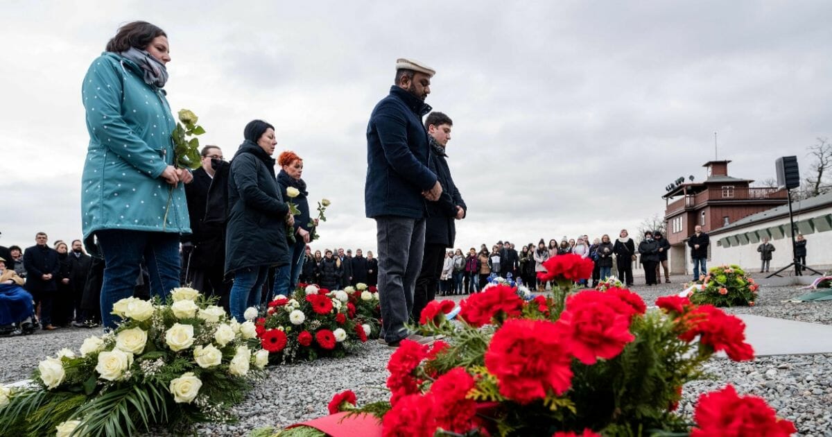 People lay flowers on a commemorative plaque during a ceremony at the memorial site of the former Nazi concentration camp Buchenwald near Weimar in eastern Germany on Jan. 27, 2020.