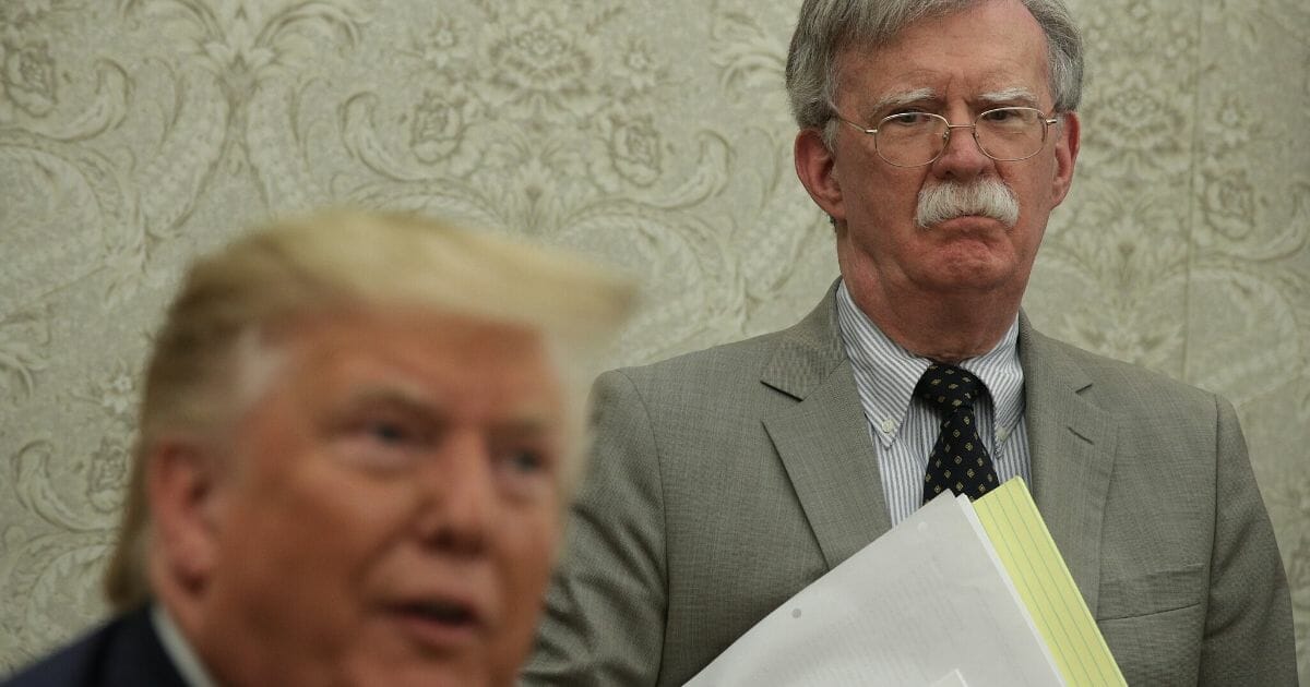 President Donald Trump speaks to members of the media as National Security Advisor John Bolton listens during a meeting with Romanian President Klaus Iohannis in the Oval Office of the White House on Aug. 20, 2019, in Washington, D.C.