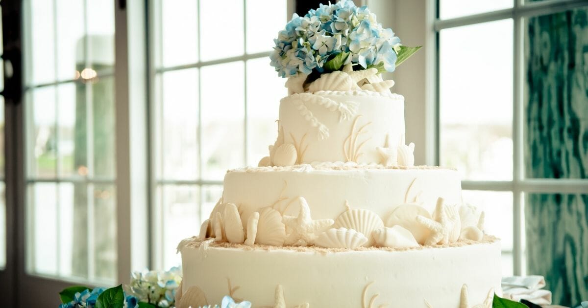 A stock photo of a wedding cake is seen above.