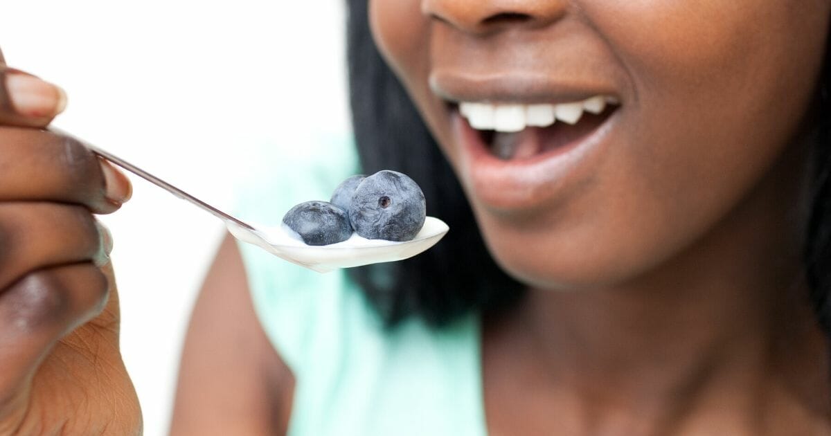 A woman is pictured above eating a spoon of yogurt.