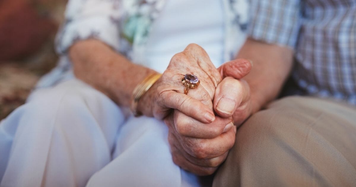 couple holding hands while sitting together