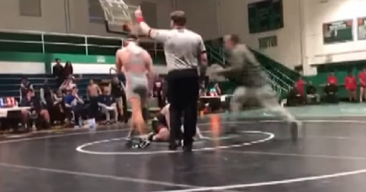 A still from a video captures a father running onto a wrestling mat to attack his son's opponent.