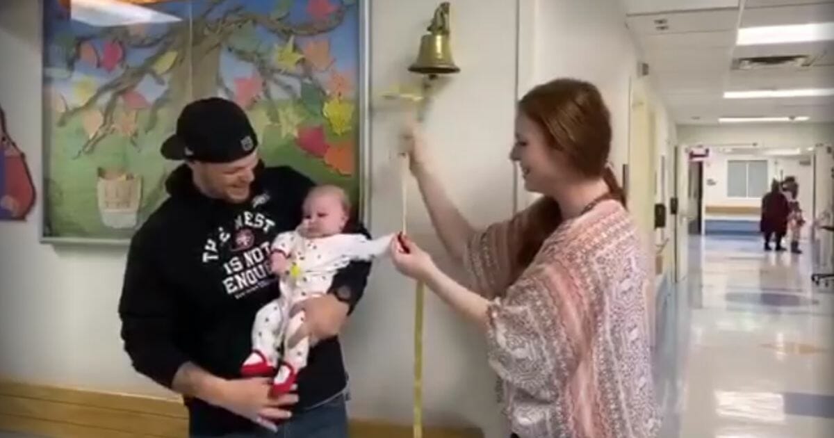 Leann Borden rings the cancer bell while husband Patrick holds their daughter, Lillian Grace.